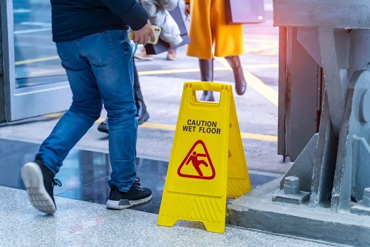 man walking by a wet floor sign which could be evidence in a slip and fall case.